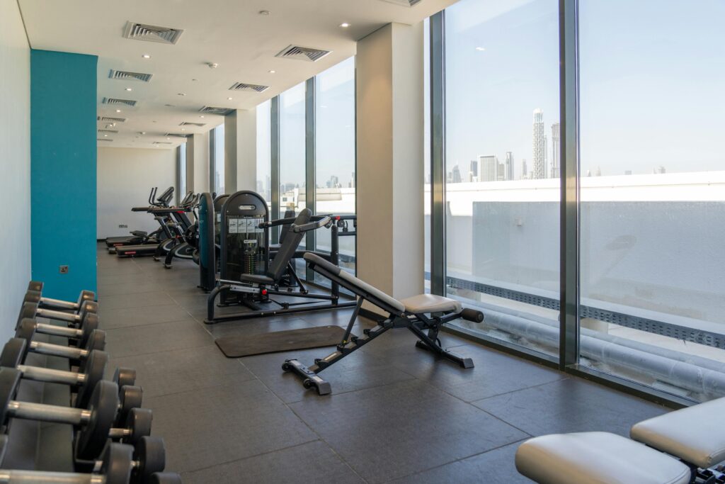 Home gym in a short-term furnished rental with treadmill, weights, and yoga space
